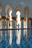 Local man in traditional clothing between the gilded columns of Sheikh Zayed Bin Sultan Al Nahyan Mosque, Abu Dhabi, United Arab Emirates, Middle East