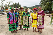 Eine Gruppe hell gekleideter Frauen, von denen die meisten lächeln, Kopfschmuck tragen und Leis halten, stehen dem Betrachter gegenüber, Rurutu, Austral-Inseln, Französisch-Polynesien, Südpazifik