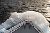 The bow of expedition cruise ship MS Bremen (Hapag-Lloyd Cruises) delves into a large swell, sending a v-shaped cloud of spray from the ship, At Sea, near South Georgia Island, Antarctica