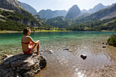 Girl in bikini sitting at Lake Seebensee with Drachenkopf mountain, Mieminger Mountains, Alps, Tirol, Austria, Europe
