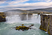 Person stood on cliff above Godafoss waterfall: Iceland, Europe