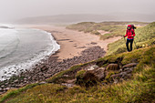Eine Wanderin bei Regen an der Sandwood Bay, Highlands, Schottland, Großbritannien