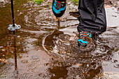 Hiking boots walking through a puddle, Inverpolly Nature Reserve, Highlands, Scotland, UK