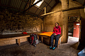 A female hiker inside the Suileag Bothy, Inverpolly Nature Reserve, Highlands, Scotland, UK
