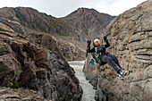 Mountaineer crosses the Rio Tunel on the Paso del Viento with a zip line (Tirolesa), Los Glaciares National Park, Patagonia, Argentina