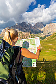 Hiker read map with Marmolada in the background. San Nicolò Pass, Fassa Valley, Trentino, Dolomites, Italy, Europe.