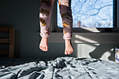 Legs of girl jumping on bed