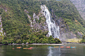 People kayaking around Bowen Falls in Milford Sound in summer. Fiordland NP, Southland district, Southland region, South Island, New Zealand.