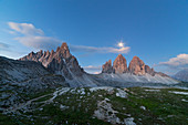 Dawn with full moon on Paterno Mount and Tre Cime di Lavaredo with Locatelli-Innerkofler refuge, Dolomites, Dobbiaco, South Tyrol, Bolzano, Italy