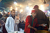 Men at a food stall on the night market. Jemaa El Fna, Marrakech, Morocco