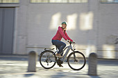 Young woman on bicycle in urban environment, Munich, Bavaria, Germany