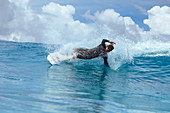 Male surfer slanting while riding wave against clouds, Male, Maldives