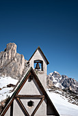 Bell tower of the chapel of San Giovanni Gualberto on the Passo di Giau in winter, in the background view of the Dolomites, Belluno, Italy