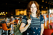 Smiling mid adult woman holding backpack in cafe