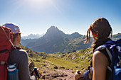 Walkers admire the view of Pic du Midi d'Ossau from the top of Col d'Ayous on the GR10 trekking route, Pyrenees Atlantiques, France, Europe