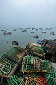 Fishing baskets and fishing boats in the fishing port of Cascais at fog, Portugal