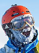 Portrait eines Extremskifahrers mit Helm und Skibrille, Schnee und Eis im Gesicht