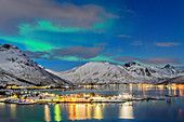 Illuminated slidpollnes and snowy mountains are reflected in fjord, Lofoten, Nordland, Norway