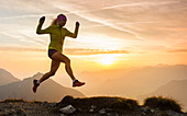 Trailrunner sprints into the air in the morning glow, Bärenkopf, Achensee, Tyrol, Austria
