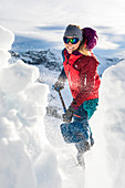 Young woman shoveling snow with an avalanche shovel, Tyrol, Austria