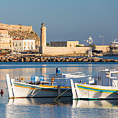 Fischerboote festgemacht in der Bucht, am frühen Morgen, historischer Leuchtturm im Hintergrund, Rethymno (Rethymnon), Kreta, griechische Inseln, Griechenland, Europa