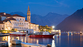 View across the illuminated harbour to waterfont mansions overlooking the Bay of Kotor, dusk, Perast, Kotor, UNESCO World Heritage Site, Montenegro, Europe