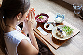 High angle view of Japanese woman sitting at a table in a Japanese restaurant, eating.