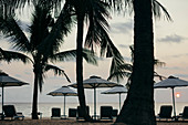 Beachside umbrellas at a luxury resort on a tropical island at sunset.