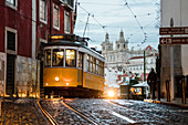 Romantische Atmosphäre in den alten Straßen von Alfama mit der Burg im Hintergrund und Straßenbahnnummer 28, Lissabon, Portugal, Europa