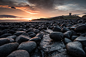 Dawn light reflecting on the rocks at Dunstanburgh Castle on the North East Coast, Northumberland, England, United Kingdom, Europe