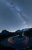 Milky Way and lights of car traces, Bernina Pass, Poschiavo Valley, Engadine, Canton of Graubunden, Switzerland, Europe