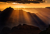 Sun rays extend from a cloud perched on the horizon putting Vishnu temple into silhouette, Grand Canyon National Park, UNESCO World Heritage Site, Arizona, United States of America, North America