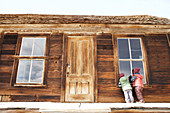 Kinder sehen durch ein Fenster in ein Haus in der Geisterstadt Bodie, Eastern Sierra, Kalifornien, USA