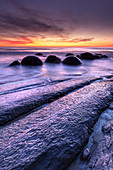 Die Moeraki Boulders mit dramatischem Sonnenaufgang am Moeraki Beach, Otago, Südinsel, Neuseeland, Pazifik