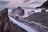 Wellen strömen um die gezackten Felsen am Wildersmouth Beach, Ilfracombe, Devon, England, Großbritannien, Europa