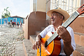 Local man singing and playing his guitar in the Plaza Mayor of Trinidad, Cuba, West Indies, Caribbean, Central America