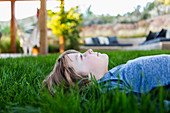 portrait of smiling 6 year old boy lying down in green grass