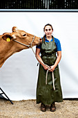 Landwirtin in grüner Schürze mit einer Guernsey-Kuh