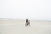 teen girl biking on sandy beach by the ocean, St. Simon's Island, Georgia