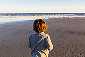 Junge beim Spazieren am Strand, ein Schwarm Möwen im Sand, St. Simon's Insel, Georgia
