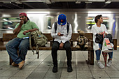 New Yorker warten auf die U-Bahn mit einer von dem amerikanischen Künstler Tom Otterness gestalteter Skulptur, unterirdisches Lebensprojekt in der U-Bahn-Station 14th Street 8 AV, Metpacking District, Manhattan, New York City, New York, Vereinigte Staaten, USA