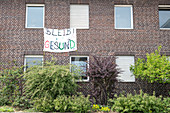 „Bleib Gesund“ Banner an Hausfassade in München, Bayern, Deutschland, Europa