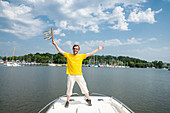 Lachender Mann steht mit der Flagge der Bretagne am Bug seines Bootes, Port Folleux, Vilaine, Departement Morbihan, Bretagne, Frankreich, Europa