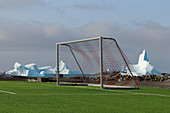 Soccer field by the sea; on the outskirts of Qeqertarsuaq; Disko Island in West Greenland; Icebergs floating off the coast frame the soccer goal;