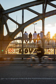 Leute sitzen zum Sonnenuntergang auf der Hackerbrücke in München, Bayern, Deutschland, Europa