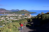 Woman on the way to the volcano with a view of Lipari, the sea and Stromboli, Vulkano Island, Aeolian Islands, southern Italy