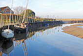 Blick auf den Kai und Liegeplätze am westlichen Ende des Hafens an der Küste von Nord-Norfolk bei Blakeney, Norfolk, England, Vereinigtes Königreich