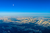 The moon rises over the Swiss mountains, aerial view