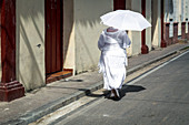 Woman with white umbrella walks along the street, Camagüey, Cuba