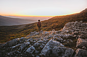 Mann steht auf Felsen in den Bergen bei Sonnenuntergang